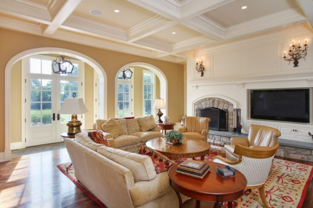 Large beige living room color with stone fireplace and coffered ceiling